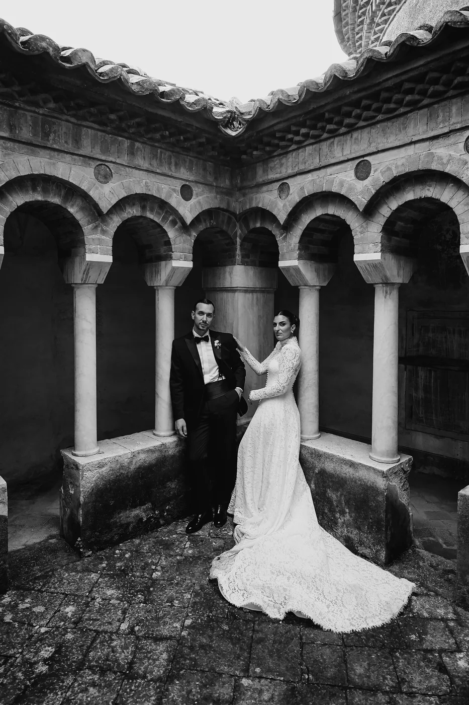 Wedding couple beneath an old stone arcade, black and white photograph by Mauro Silvestre